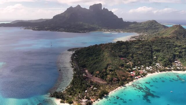 Stunning drone panoramic shot showcasing the majestic volcanic peak of Mount Otemanu rising above the vibrant turquoise lagoon and lush ridges of Bora Bora