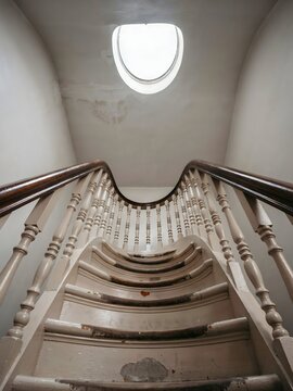 Curved wooden staircase rising toward oval skylight in old house &ndash; Ideal for renovation features, historic interior design, or property content