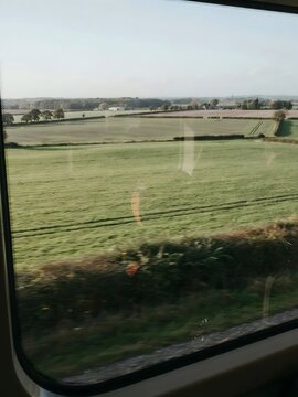 Sunlit farmland seen through moving train window &ndash; Great for rail travel promotions, countryside tourism, or slow travel content