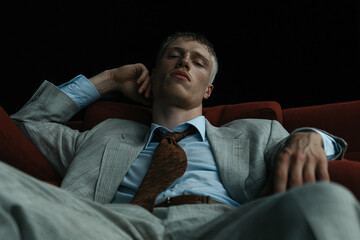 Fototapeta premium Relaxed Businessman in Suit on Dark Sofa