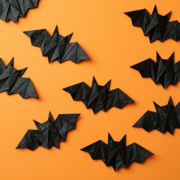 Black origami bats scattered on orange background