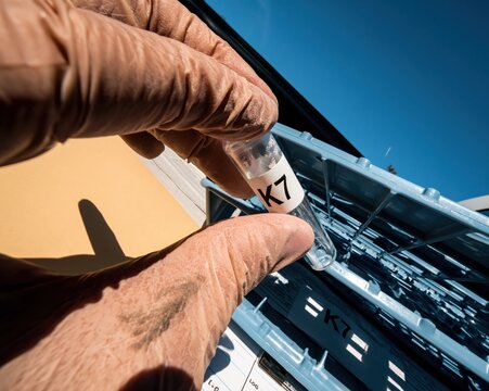 Gloved hand holding a cryovial with a K7 label, featuring frosted glass and a smudge on the nitrile glove for personalized medicine and cancer research