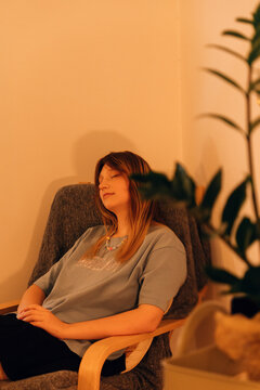 Young woman relaxes with closed eyes in a comfortable chair after a wellness session. Peaceful recovery scene for spa, stress relief and self care.