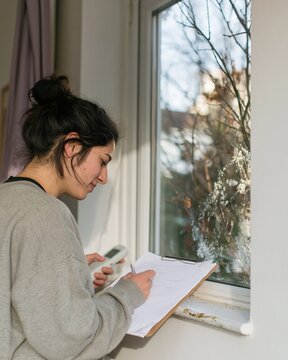 Winter home energy audit by a woman using a handheld reader on a frosted window, checking heating maintenance for efficiency services