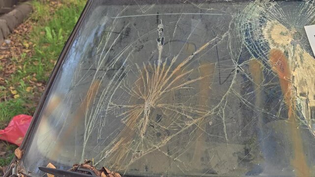 A broken car windshield with a sticker on it
