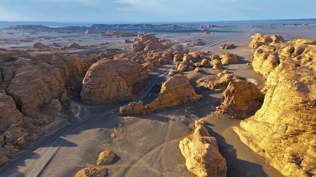 Aerial panorama of eroded yardang rock formations and a winding desert road in Dahaidao, Xinjiang, China, ideal for adventure travel and geology themes.