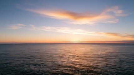 Obraz premium Calm ocean under a soft clouded sky at sunset, featuring muted teal water and a glowing peach horizon for meditation and travel backgrounds