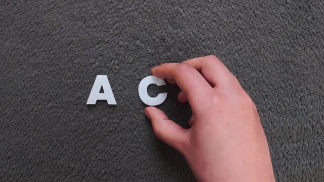 persona escribiendo la palabra acv en un fondo texturizado y oscuro con letras blancas y pre hechas (version lenta)