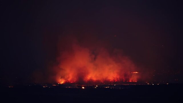 Smoke rising from a wildfire burning at night in the Utah desert at the Tom Creek fire.