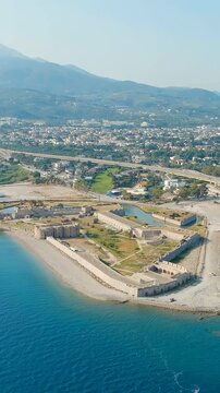 Vertical video. Patras, Greece. Rio Fortress and the Charilaos Trikoupis Bridge, a pentagonal Ottoman fortification beside the world's longest multi-span cable-stayed bridge, Drone footage over the G