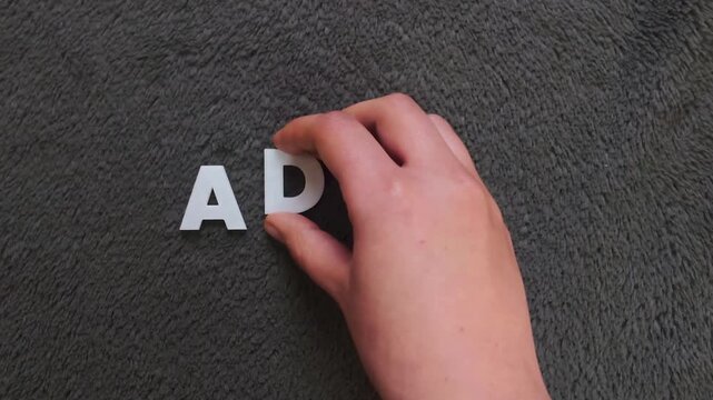 The word adhd written on a dark background with white uppercase block letters (slow version)