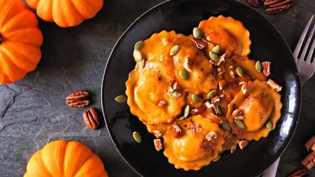 Pumpkin filled ravioli pasta with nuts and pumpkin seeds. Table scene, above view on a dark background. Slow rotating zoom motion.