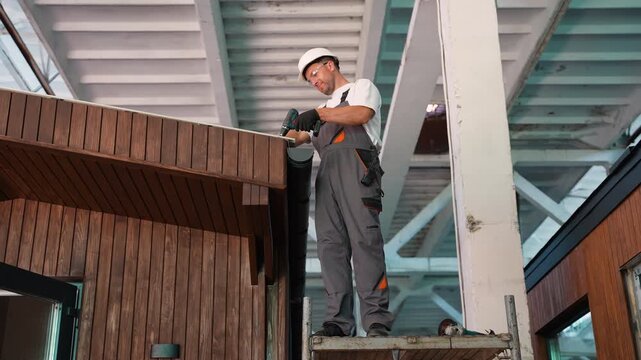 Professional roofer installing gutter system on modular house