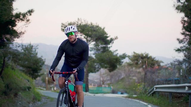 Athletic man doing road cycling in the landscape of the gi. Sport fitness and healthy lifestyle riding a bike on the highway.