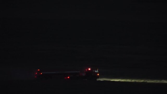 Fire tanker truck driving on a dirt road at night in the Utah desert as it hauls water to fight the Tom Creek wildfire.