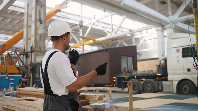 Construction foreman supervising modular house loading in a factory