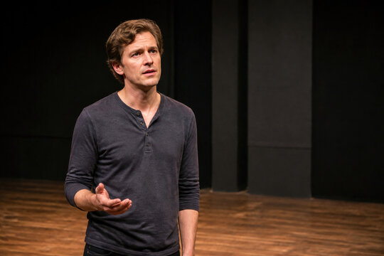 Actor rehearsing a scene on stage, expressing emotion and using gestures during dramatic performance