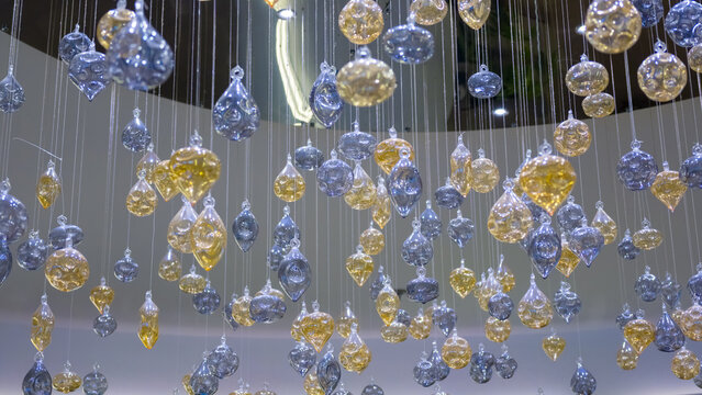Modern Interior Glass Chandelier Installation Featuring Hanging Amber and Silver Glass Drop Ornaments Suspended from Ceiling