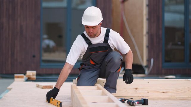Professional carpenter measuring and leveling a wooden beam on a construction site