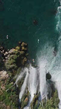 Amazing aerial view of adventure scenery with people paddling under waterfall