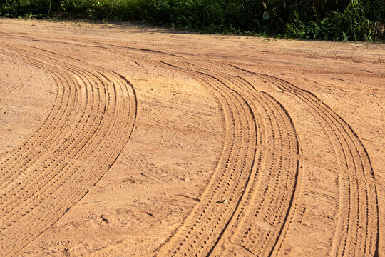 Parallel truck tracks on a red dirt road with lush green vegetation in the background