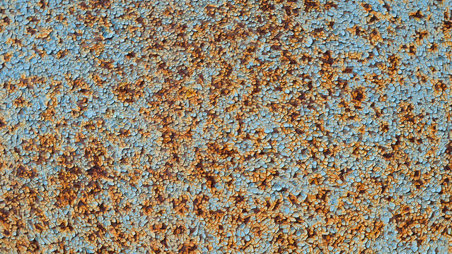 Close-up of corroded metal with orange rust spots. Blue paint is heavily damaged in spots. Rust texture looks uneven and speckled. Metal background has extensive corrosion