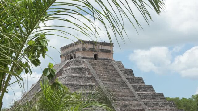 Kukulkan pyramid at Chichen Itza with swaying palm leaves