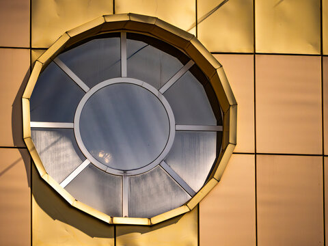 Modern Circular Window on Golden Metal Cladding Facade of Contemporary Building