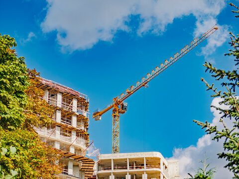 Construction site with tower crane and unfinished apartment building against blue sky