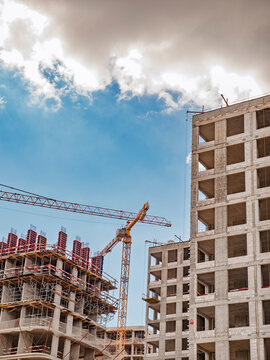 Modern construction site with unfinished high-rise buildings and a tower crane against a blue sky