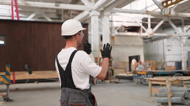 Construction foreman managing loading of a modular house with walkie talkie