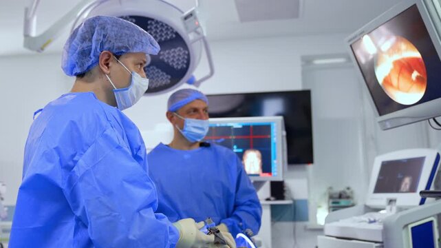 Neurosurgeons working at operation look attentively at the screen in front of them. Modern operating room with the ongoing neurosurgical operation.
