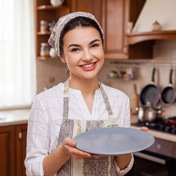 Happy housewife holds a clean plate in her hands