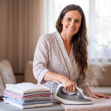 Young beautiful housewife ironing clothes at home