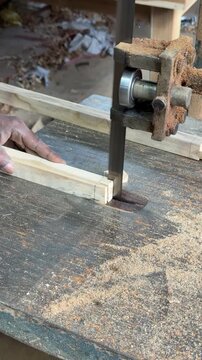 Carpenter Cutting Wood On Electric Band Saw Machine. Vertical video close up of craftsman slicing timber on industrial band saw in workshop. Ideal for woodworking ads.