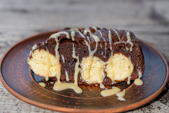 Slice of marble cake or cottage cheese chocolate pie with sweet glaze. Delicious slice of chocolate marble cake filled with cottage cheese balls and drizzled with sweet condensed milk glaze, close up