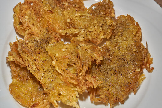 Close-up of homemade potato pancakes with a golden crispy crust and a texture of coarsely grated potatoes. Golden crispy potato pancakes made from freshly coarsely grated potatoes.