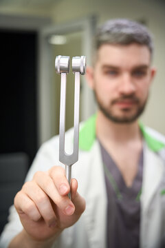 Caucasian man holding tuning fork in medical office during day