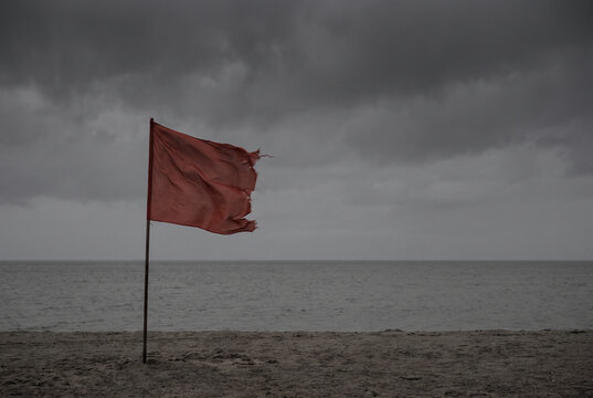 Storm Warning Flag on Empty Beach Under Dark Sky