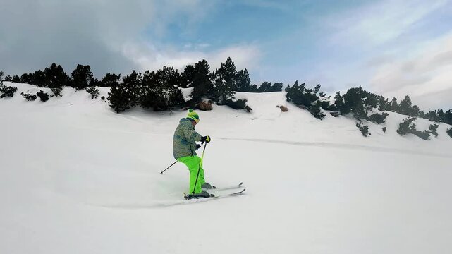Borovets, Bulgaria - Feb 12, 2025: Skier in bright gear glides downhill on a snowy slope surrounded by mountain vistas in Borovets, Bulgaria