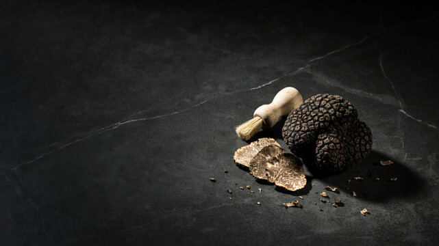 Black truffle and slicer on dark stone surface for gourmet culinary use