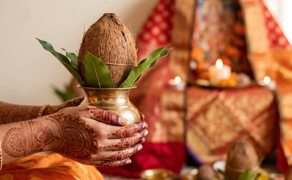 Indian woman with henna hands holding kalash with coconut and mango leaves for traditional puja ceremony