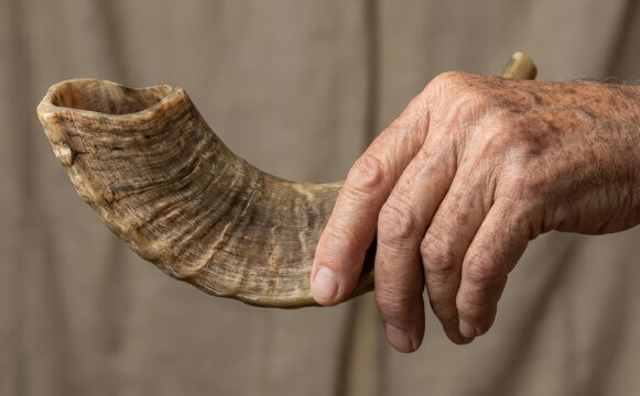 Elderly man holding a traditional ram shofar horn for Jewish holiday celebration