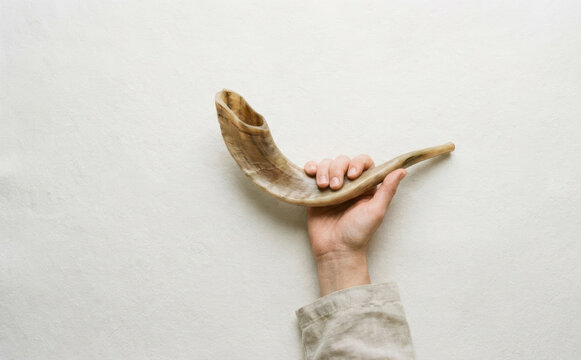 A person holding a traditional Jewish shofar horn for Rosh Hashanah celebration and religious rituals