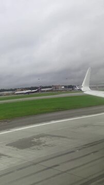 Overcast day at an airport runway with plane wing and terminal view