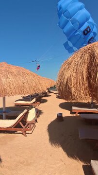 Tropical beach scene with straw umbrellas and parasailing adventure.Egypt. Hurghada.
