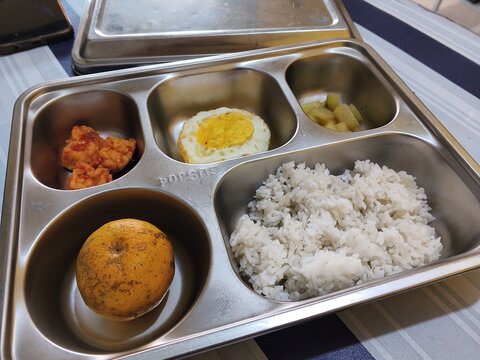 School lunch tray containing rice egg fruit fried chicken and pickles for a balanced meal