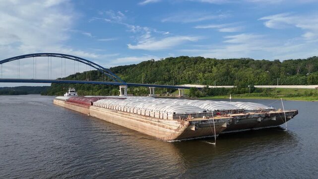 Panning view of a Tug boat pushing a large set of barges South down  the Mississippi River