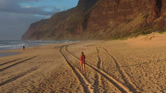 Drone Following Woman Walking on Polihale Beach at Golden Hour, Kauai