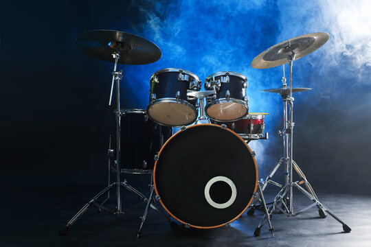 Drum set on dark background with blue light and smoke. Musical instrument